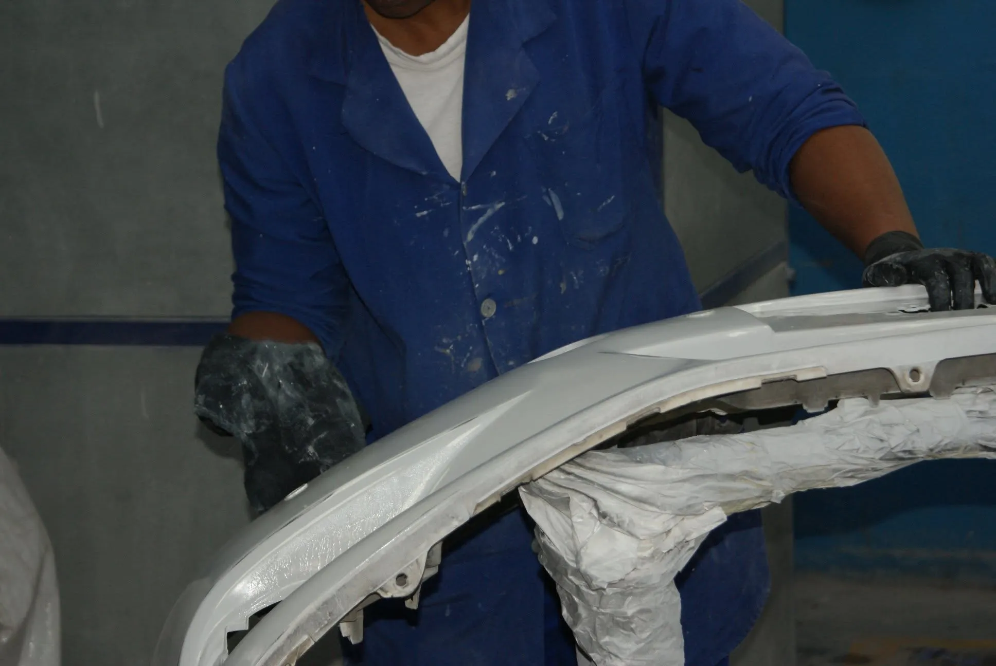 Unique Panel & Spray technician repairing a damaged front bumper