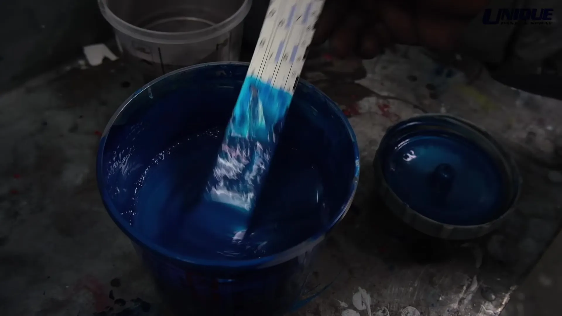 Blue paint being mixed in a tin for a colour-matched vehicle refinish